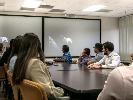 Professor and students of aerospace and mechanical engineering discuss space image on classroom screen. 