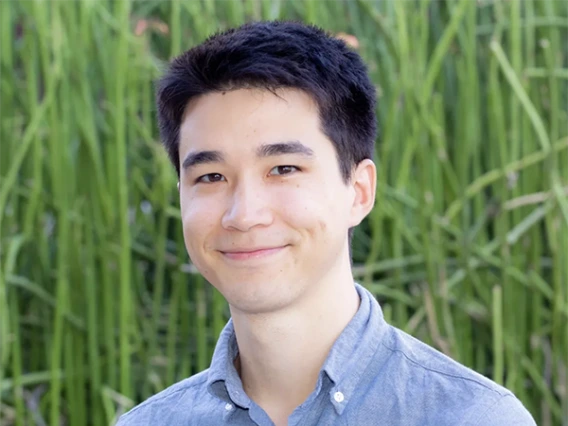 portrait of man in blue shirt in front of grassy background