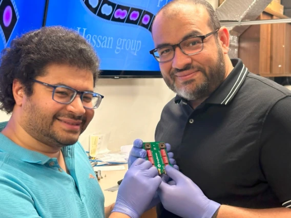 Mohammed Hassan (right), associate professor of physics and optical sciences, and Mohamed Sennary, a graduate student studying optics and physics, holding the commercial transistor they used to develop a petahertz-speed transistor.