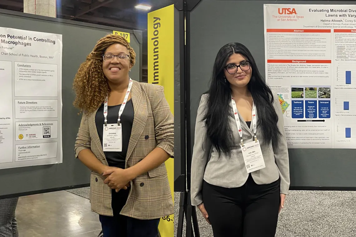 Two students standing by their posters at a conference