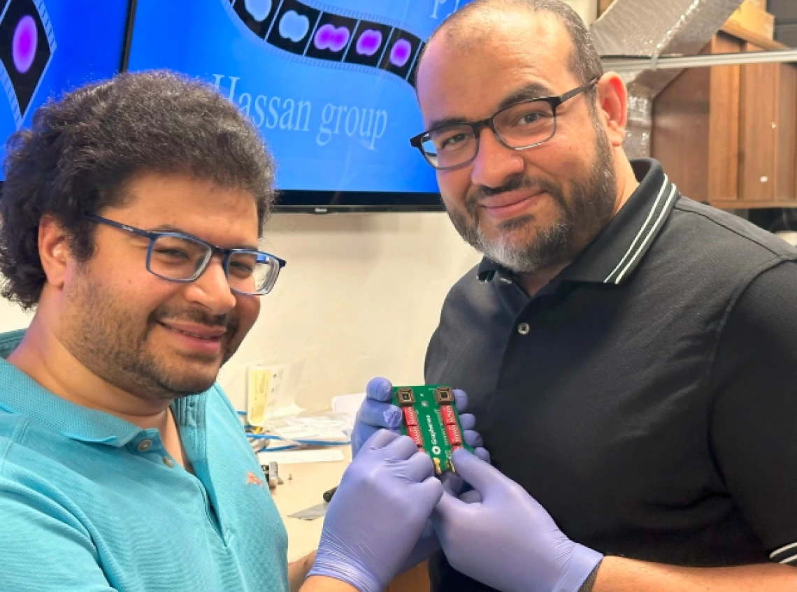 Mohammed Hassan (right), associate professor of physics and optical sciences, and Mohamed Sennary, a graduate student studying optics and physics, holding the commercial transistor they used to develop a petahertz-speed transistor.