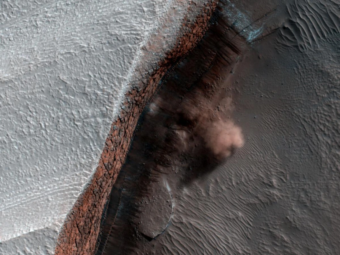 A cloud of dust rolls out from an avalanche at the base of a cliff on Mars’ north polar ice cap. The image was captured in 2010 by the University of Arizona’s HiRISE camera onboard NASA’s Mars Reconnaissance Orbiter.